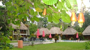 A resort with thatched-roof huts, outdoor seating, and a swimming pool. - Hotel Tikal Inn (Flores)