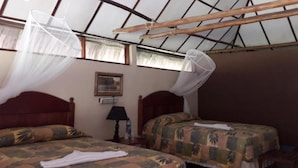A room with two beds, each with mosquito nets, wooden headboards, and patterned bedspreads. - Hotel Tikal Inn (Flores)