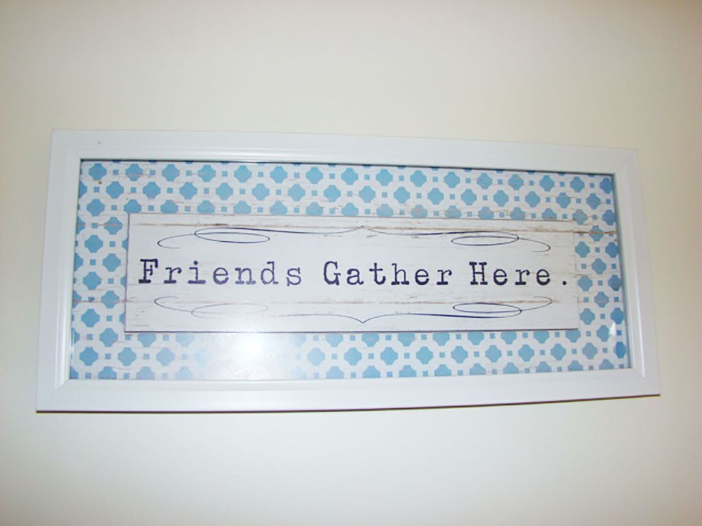 A framed sign with the text 'Friends Gather Here.'