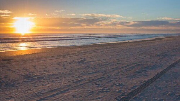 A beach with a sunset, waves, and a clear sky. - Ocean Gate at Hibiscus Resort (St. Augustine)