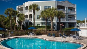 A pool area with lounge chairs and a building with multiple balconies. - Ocean Gate at Hibiscus Resort (St. Augustine)