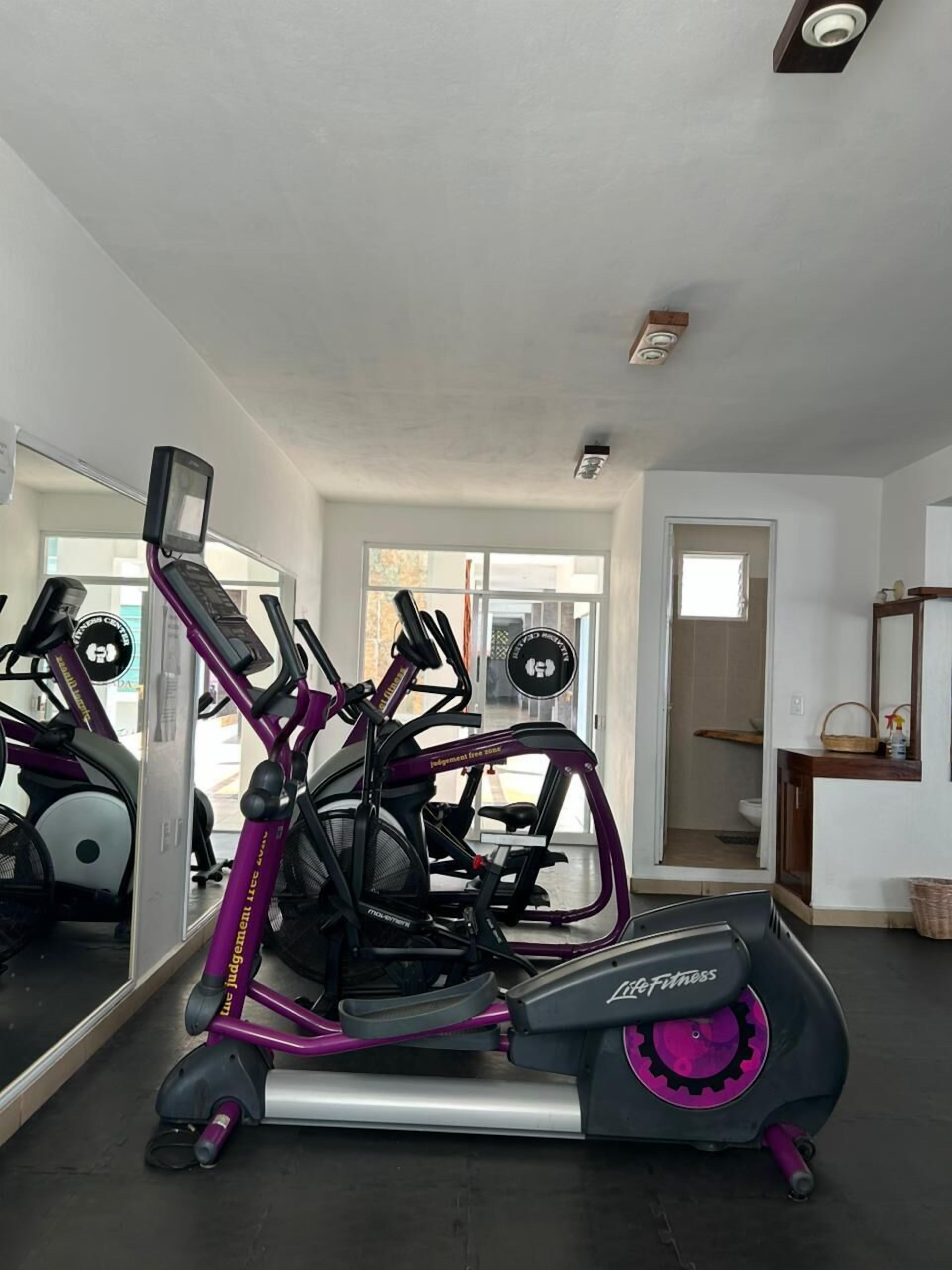 Una palestra in casa con cyclette, ellittica e tapis roulant.