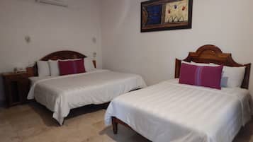Habitación de hotel con dos camas, cabecero de madera, mesita de noche con teléfono y aire acondicionado de pared.