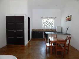 Una cocina compacta con zona de comedor, un armario negro y una ventana con cortinas.
