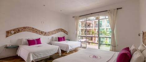 Habitación de hotel con dos camas, un ventanal con vistas a un edificio y palmeras, y una pared decorativa de piedra.