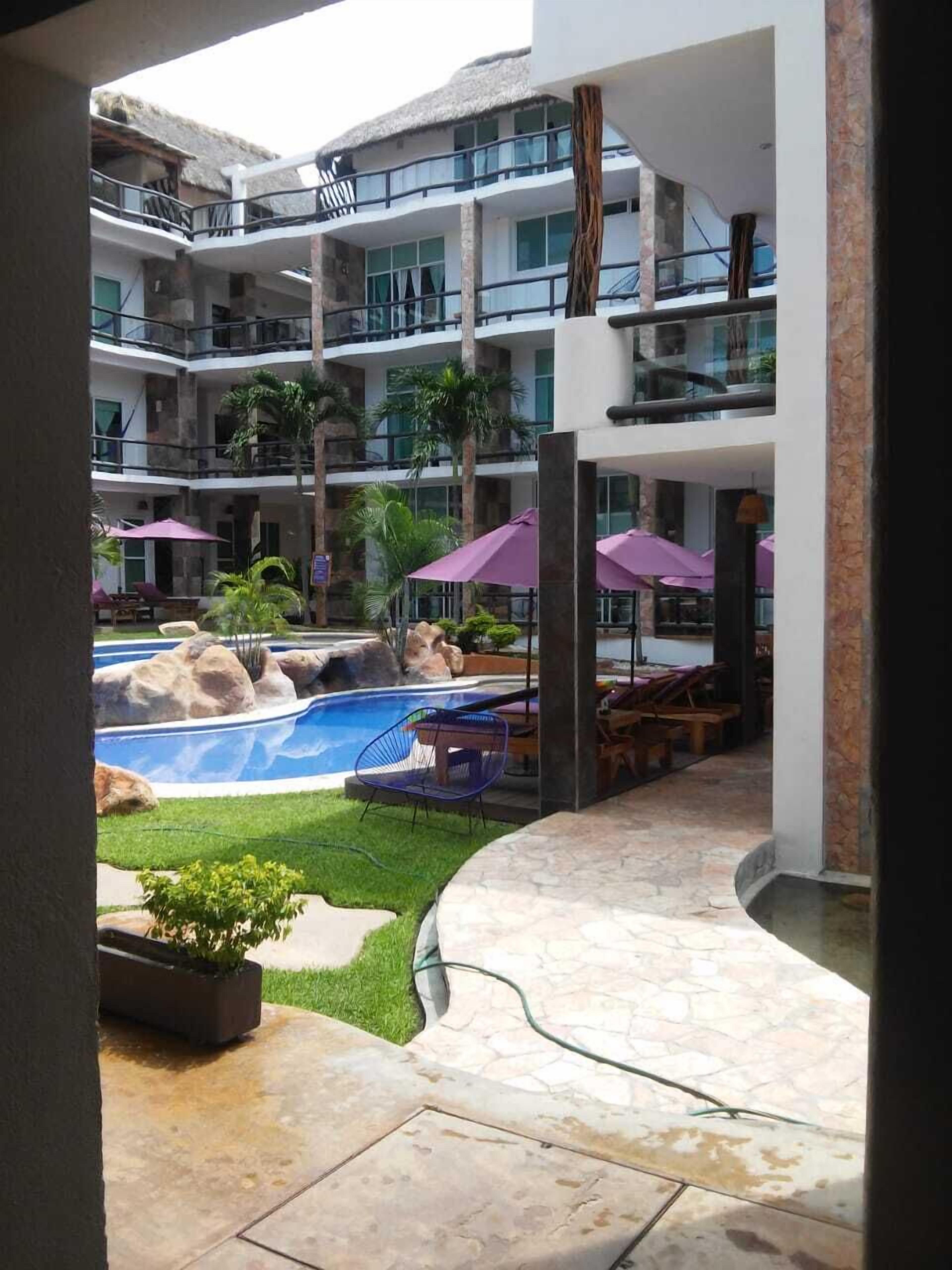 A hotel courtyard with a swimming pool, lounge chairs, and umbrellas.