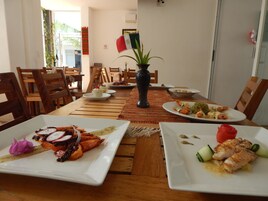 Un comedor con mesas y sillas de madera, un florero con una planta y platos de comida.