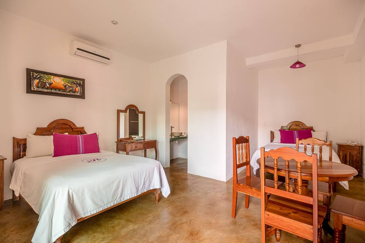 Un dormitorio con una cama, una silla de madera, una mesa y un espejo.