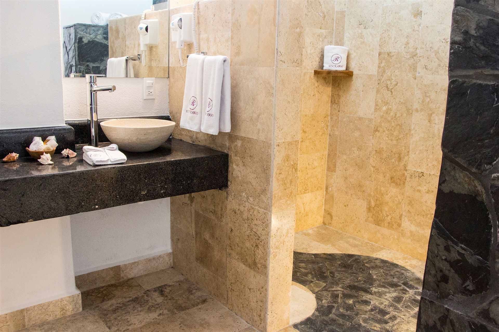 Une salle de bain avec un grand lavabo, un miroir, un porte-serviettes et un espace douche.