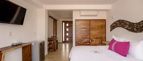 Une chambre d’hôtel avec un lit, un téléviseur fixé au mur, un bureau en bois et une armoire.