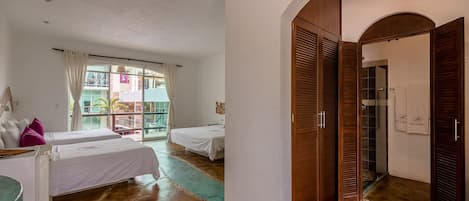 A hotel room with two beds, a large window, and a wooden wardrobe.