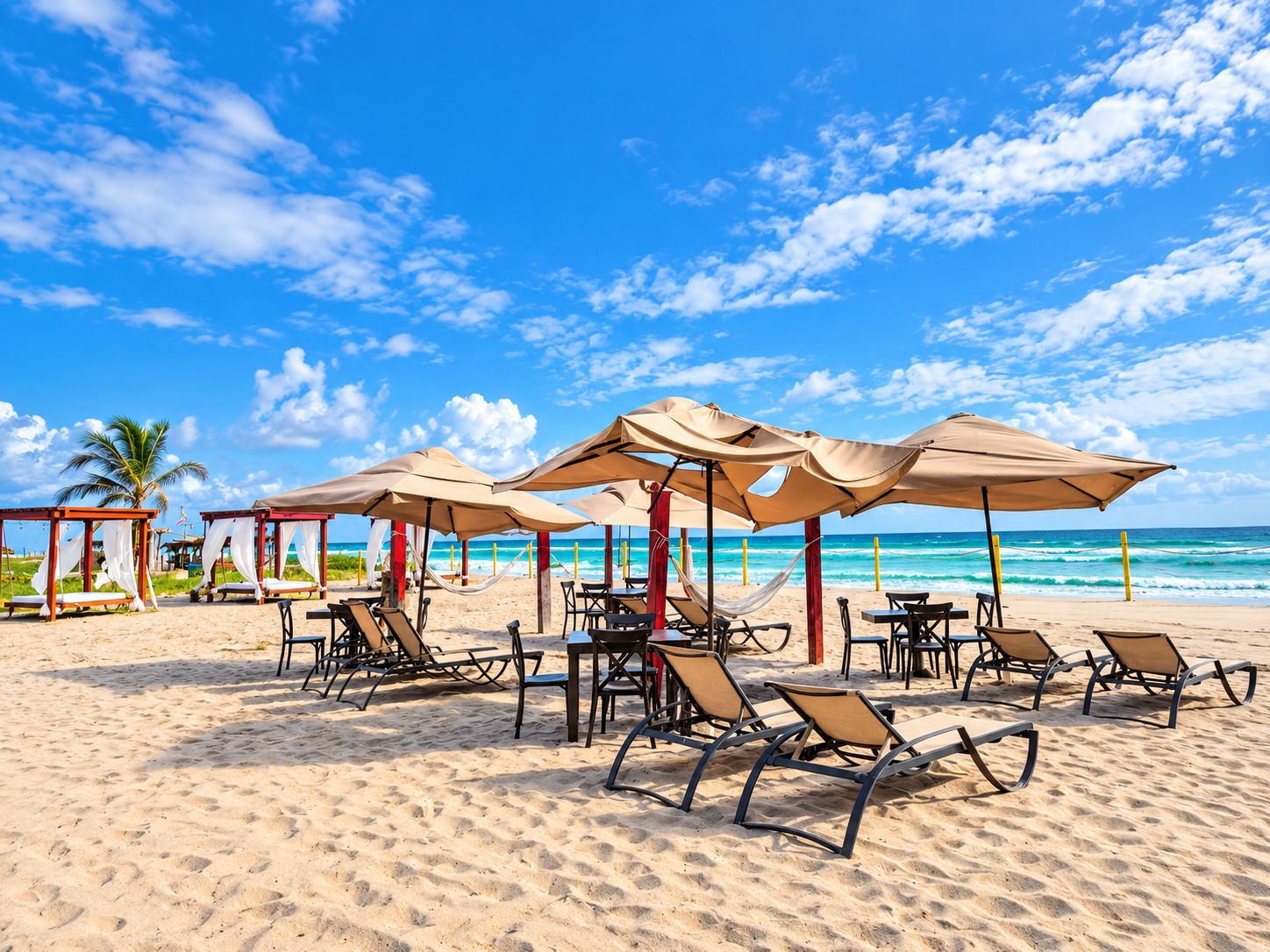 Een strand met ligbedden, tafels en parasols.