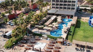 Un resort con piscina, comedor al aire libre y un edificio grande de varios pisos.