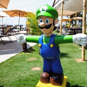 A Mario statue outdoors with a grassy area and umbrellas in the background. - Mishol Bodas Hotel & Beach Club Acapulco Diamante (Acapulco)