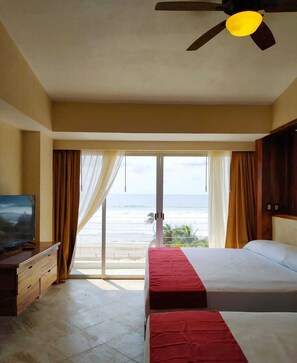 A hotel room with two beds, a ceiling fan, a TV, and a view of the ocean. - Mishol Bodas Hotel & Beach Club Acapulco Diamante (Acapulco)