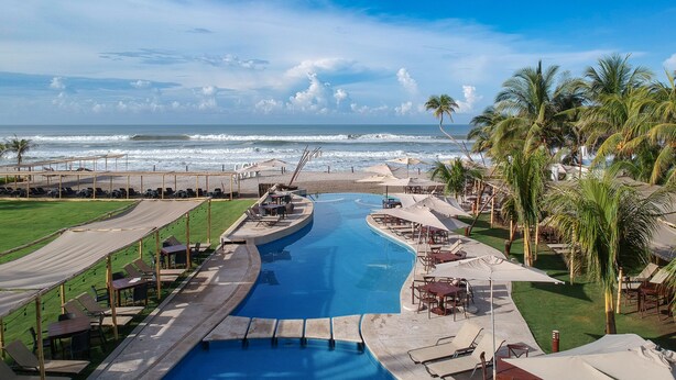 Un resort con piscina, zona de playa y vista al océano.