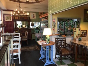 A cozy dining area with a table, chairs, and a lamp. There is a window with a view of the street, and a wall with a no smoking sign.
