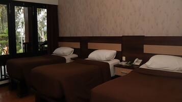 Habitación de hotel con tres camas individuales, suelo de madera, un ventanal grande y pared con diseño.