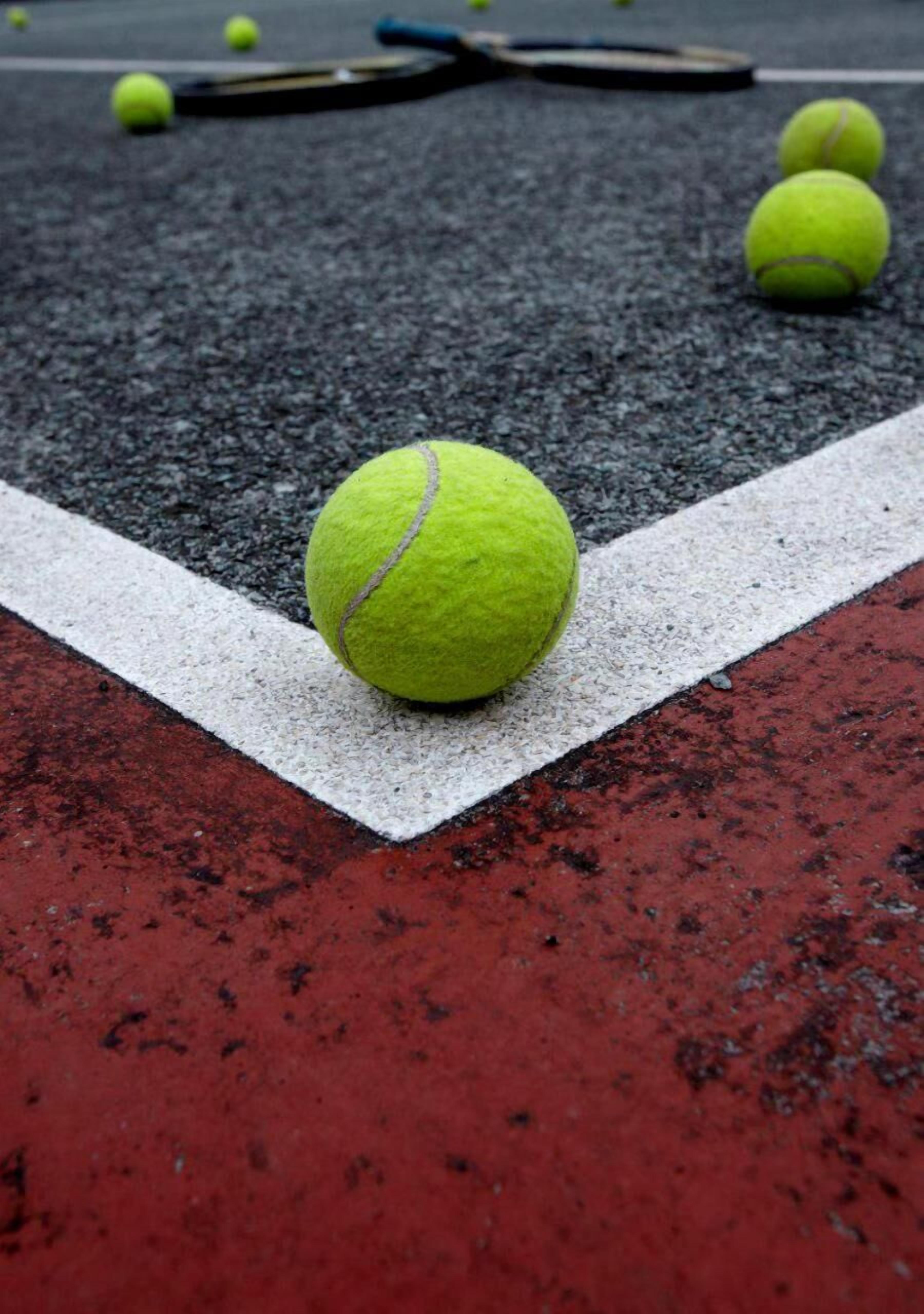 Uma bola de tênis em uma quadra com uma linha divisória branca.