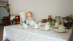 A table set with white teacups, saucers, and a teapot, surrounded by various food items and kitchenware. - Wangnong Resort (Ubon Ratchathani)