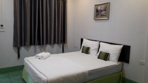 A neatly made bed with white linens and two pillows, a framed picture on the wall, and a window with dark curtains. - Wangnong Resort (Ubon Ratchathani)