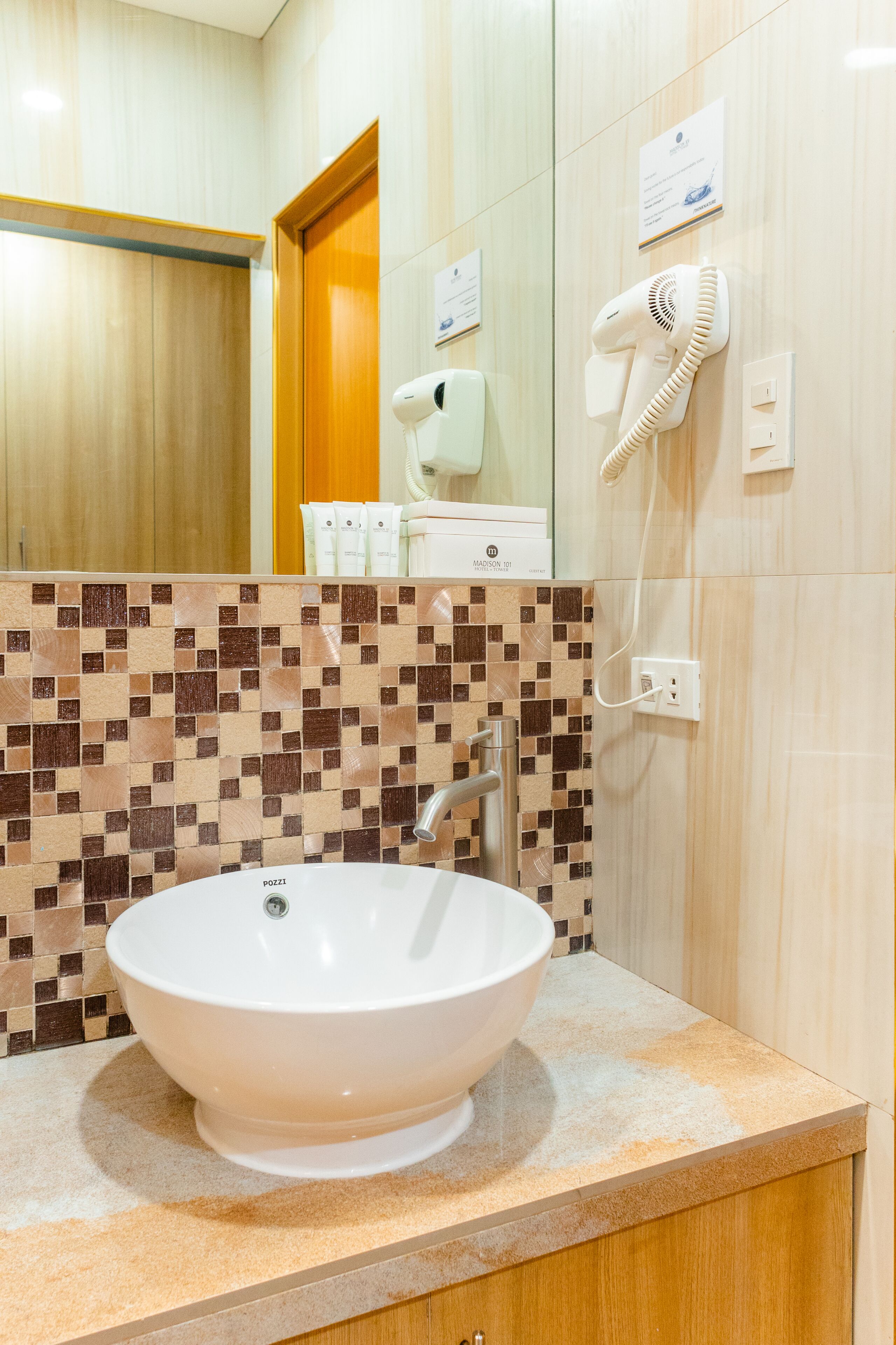 A bathroom with a white sink, a mirror, and a hairdryer mounted on the wall.