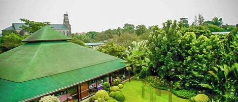 A building with a green roof, surrounded by well-maintained gardens and a small bridge.