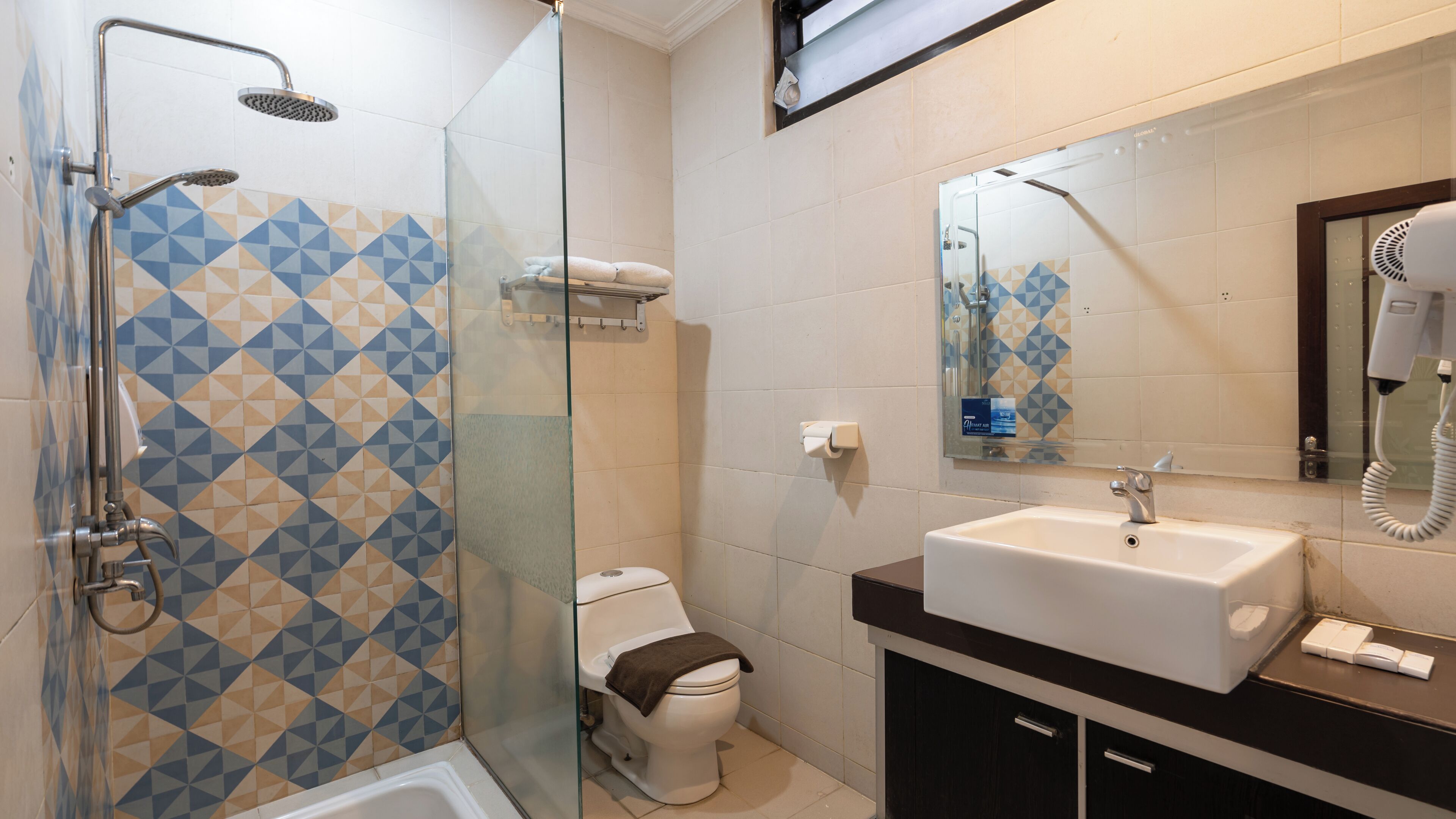 A modern bathroom with a glass-enclosed shower, a white toilet, and a sink with a mirror above it.