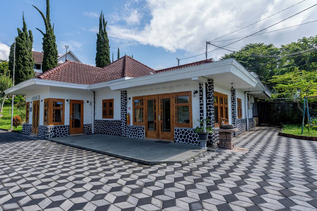 A two-story house with a tiled roof, large windows, and a paved driveway.
