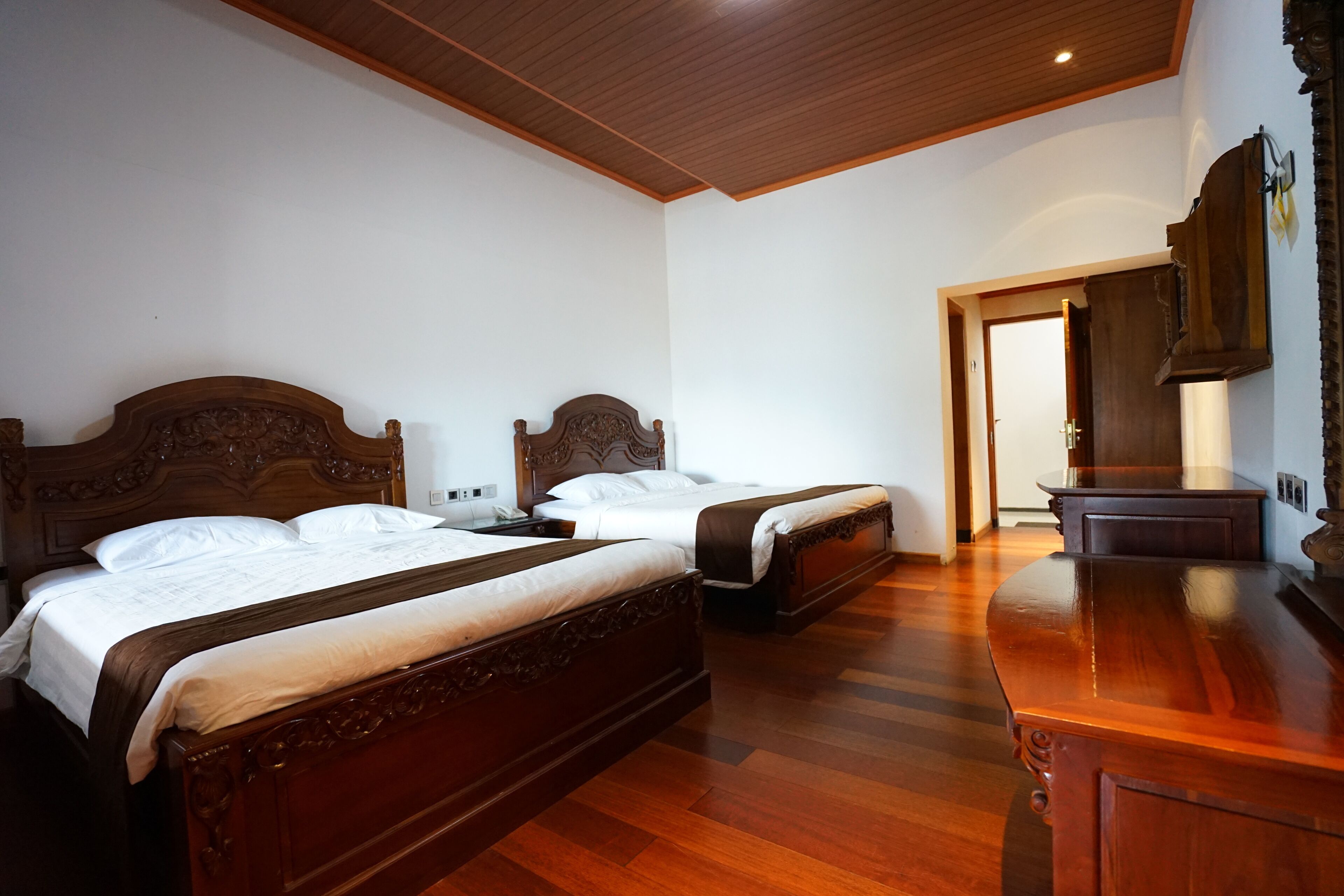 Una habitación de hotel con dos camas de madera, un aparador de madera y techo de madera.