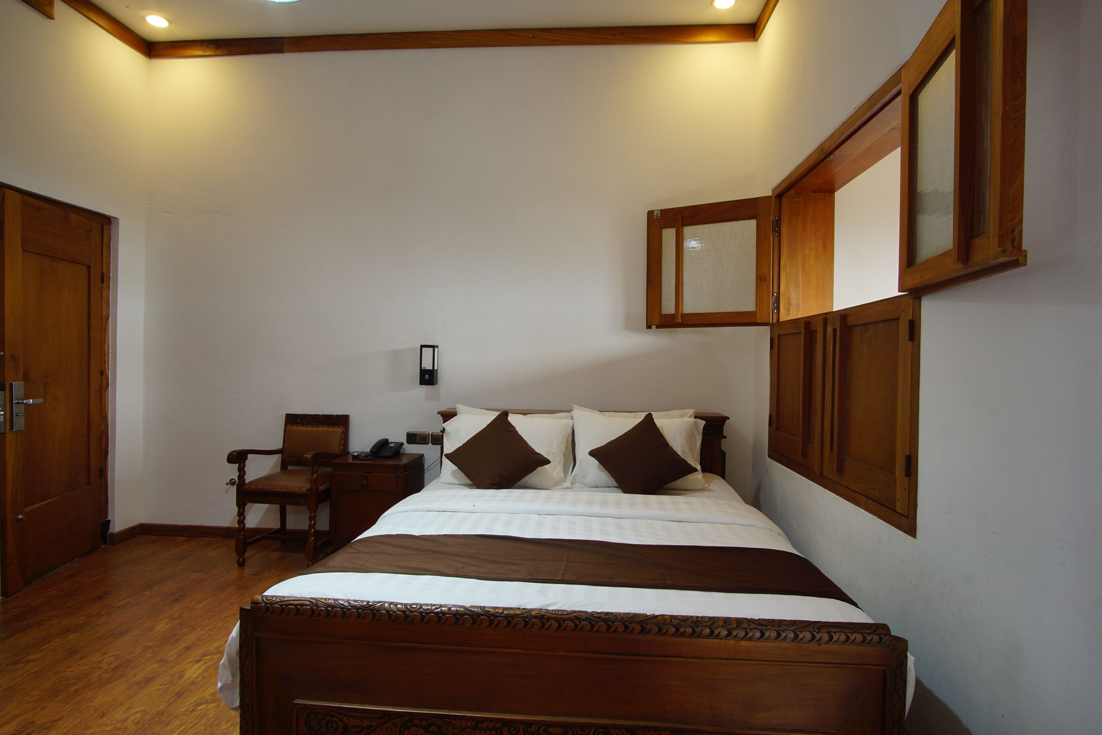 A neatly arranged bedroom with a wooden bed, a chair, and a nightstand.