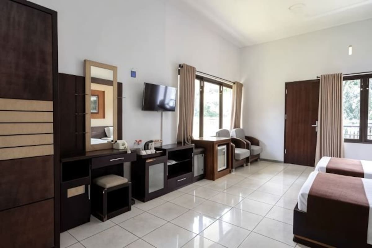 A hotel room with a bed, a desk, a chair, a TV, and a window.