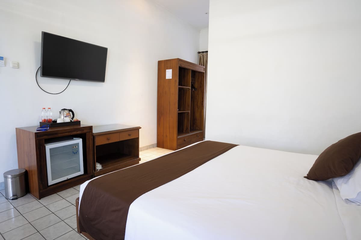 A hotel room with a bed, a desk, a television, and a wardrobe.