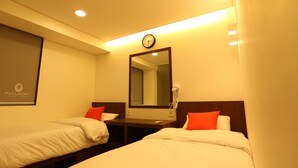 Une chambre d’hôtel avec deux lits simples, une table de chevet, un miroir, une horloge et un sèche-cheveux.