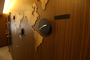 A wall clock with a world map design and a sign indicating 'New York'.