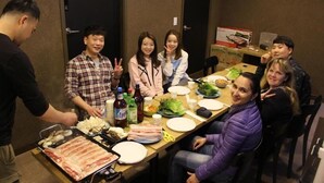 Un groupe de personnes est assis autour d’une table, devant divers plats et boissons.