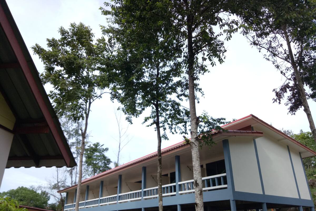 A two-story building with a balcony, surrounded by trees.