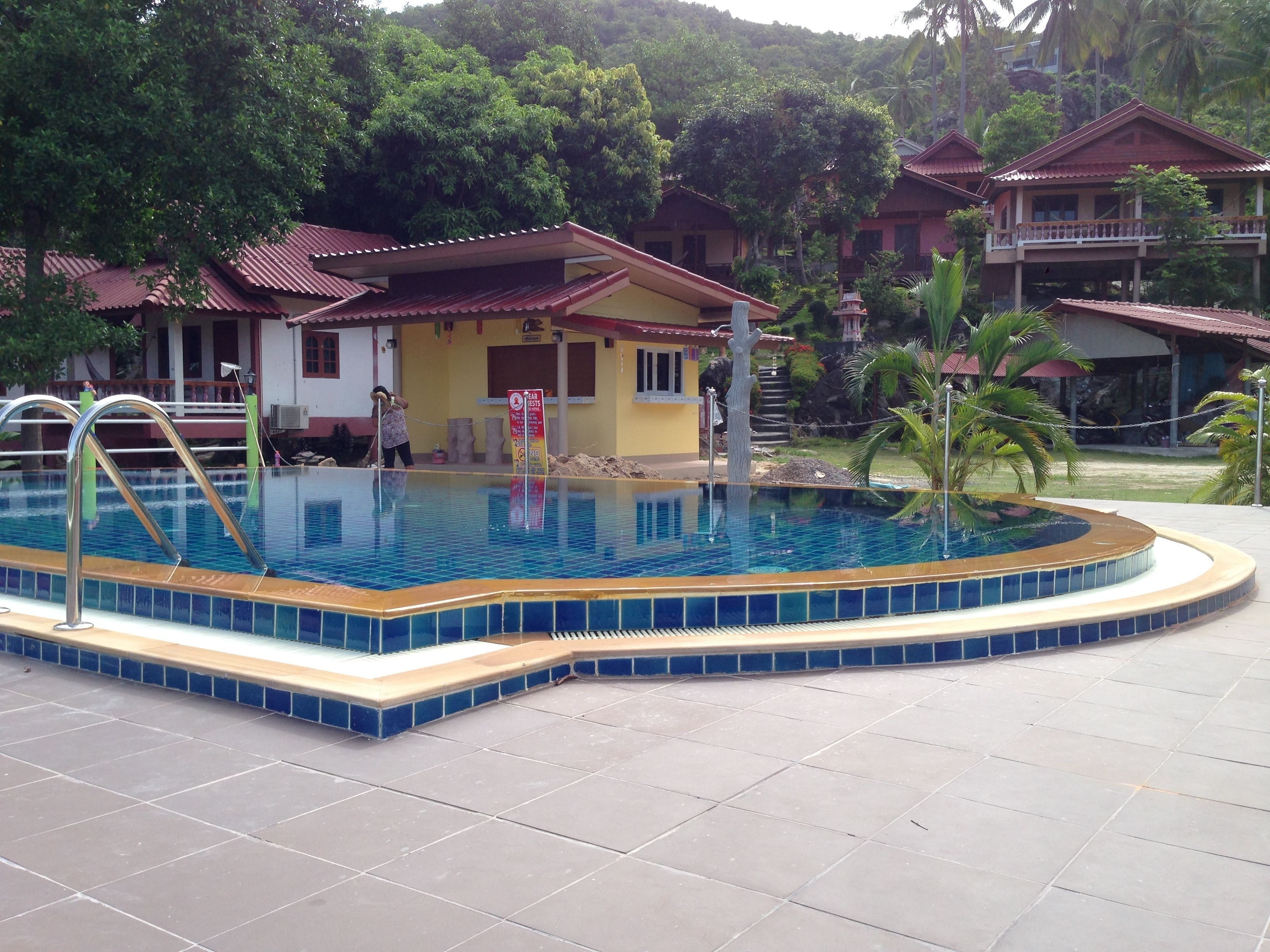 A swimming pool with a tiled edge, surrounded by a tiled deck.