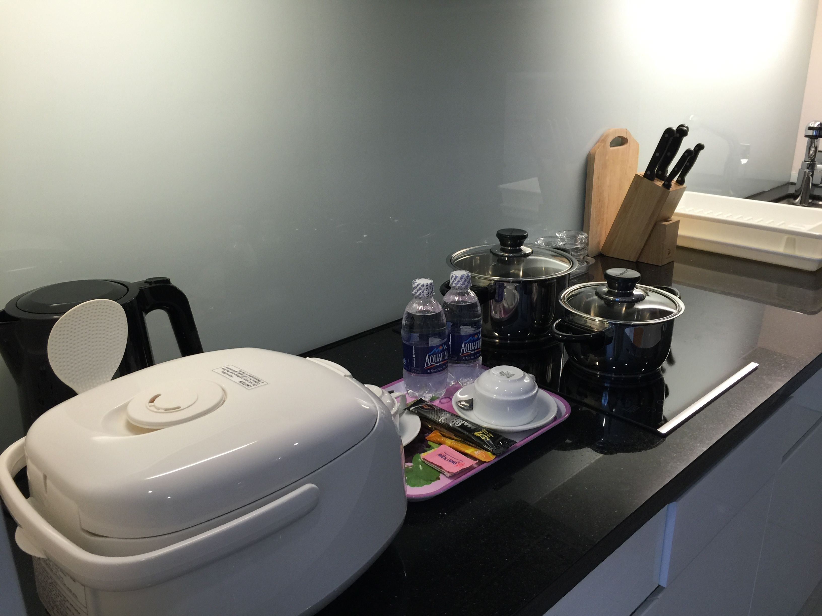 A kitchen counter with a coffee maker, a kettle, a toaster, a knife block, and some food items.