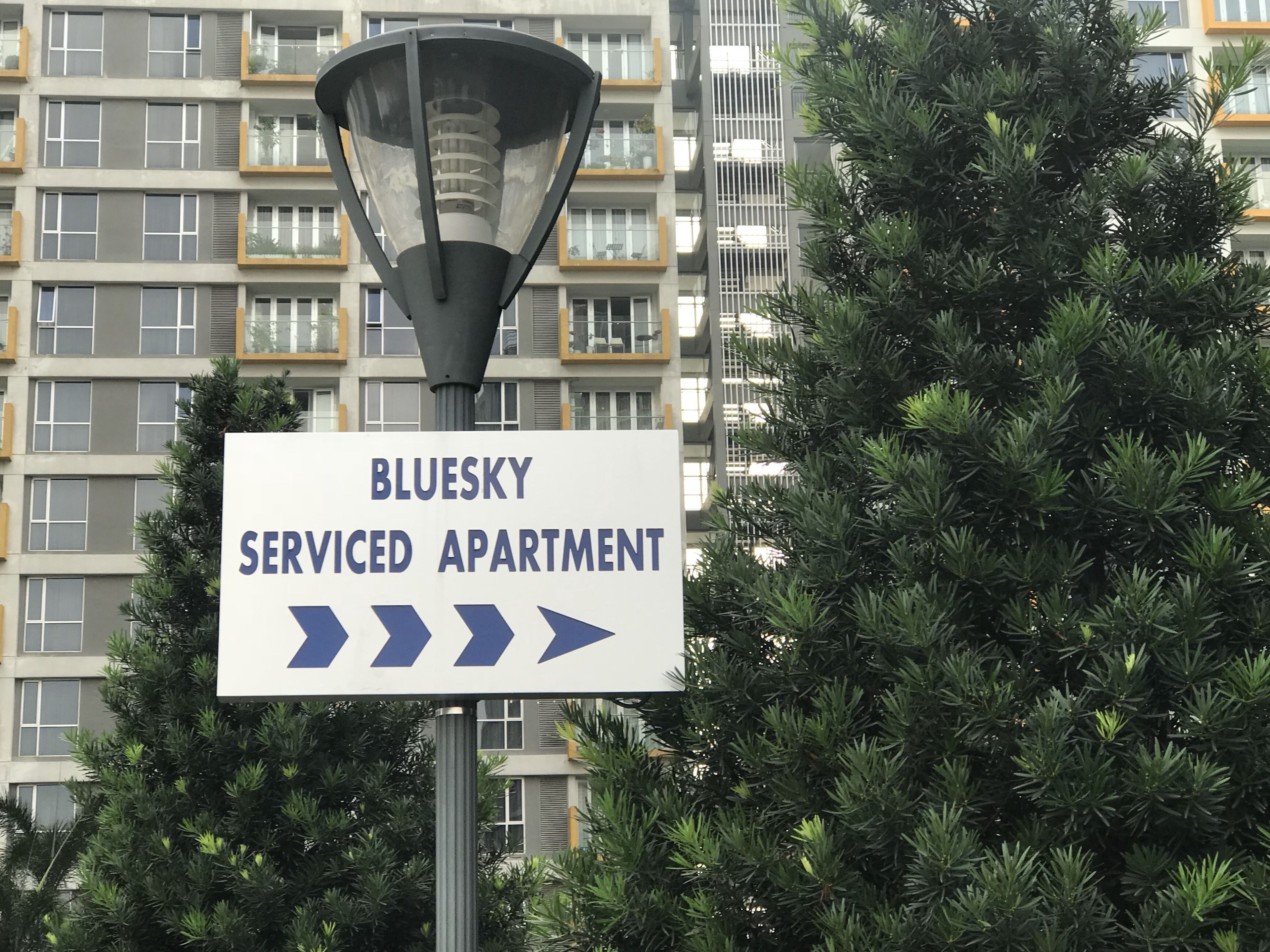 A sign for 'Bluesky Serviced Apartment' with directional arrows.