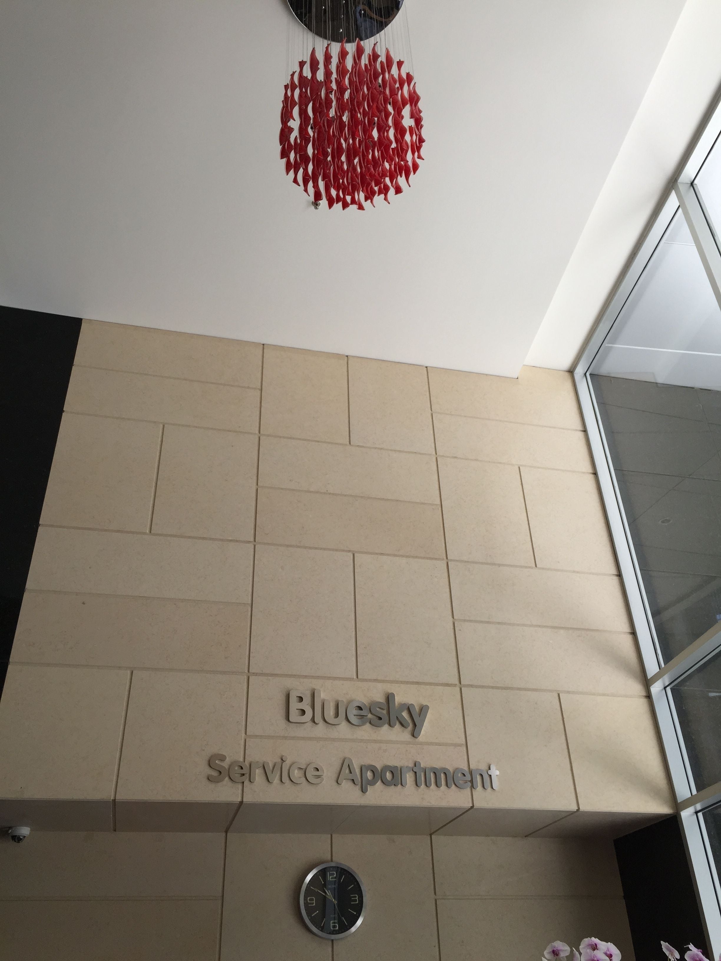 Señal de apartamento con servicios, un reloj y un adorno rojo colgante.