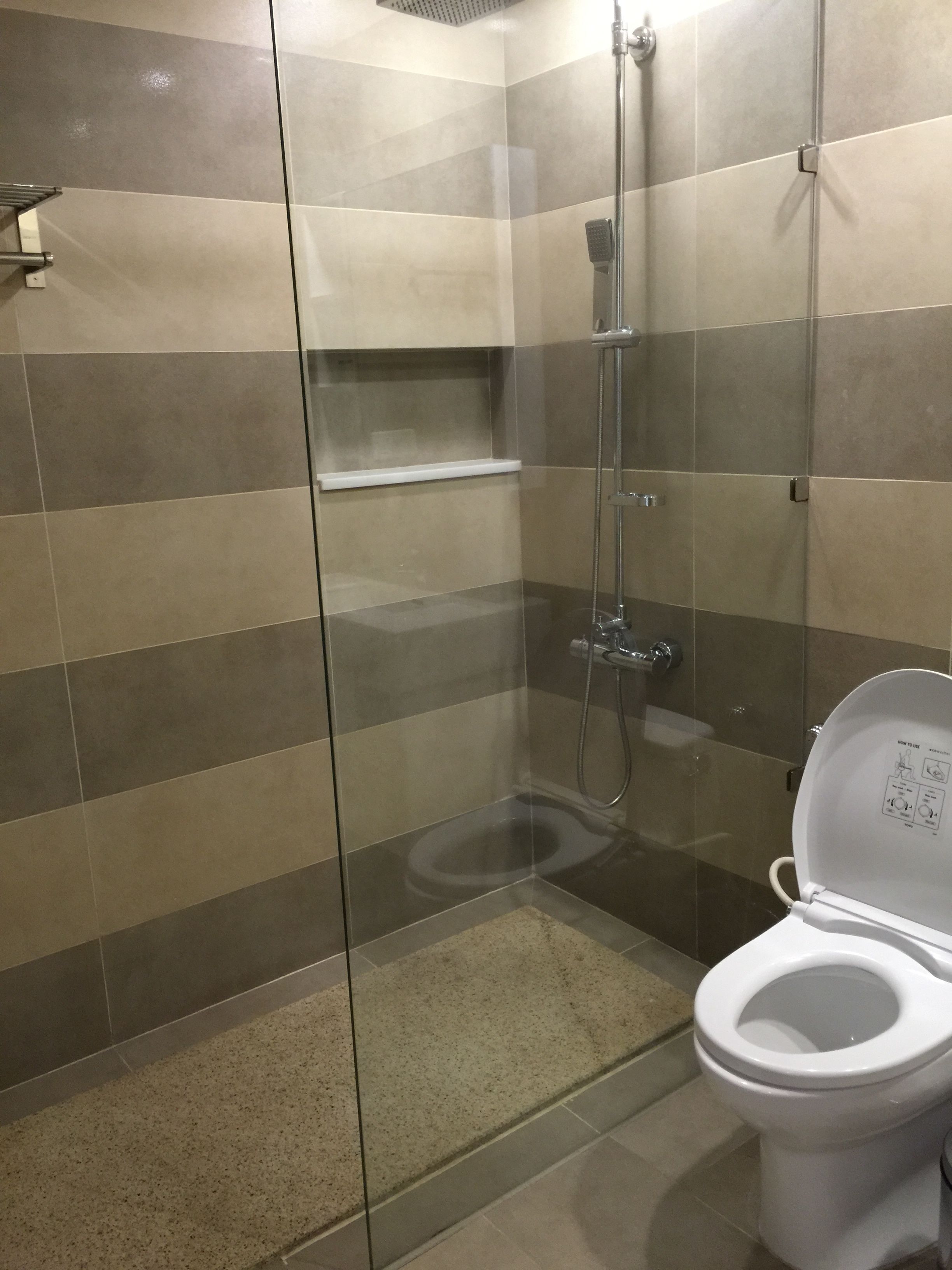 Een moderne badkamer met een douchecabine van glas, een toilet en een wandplank.