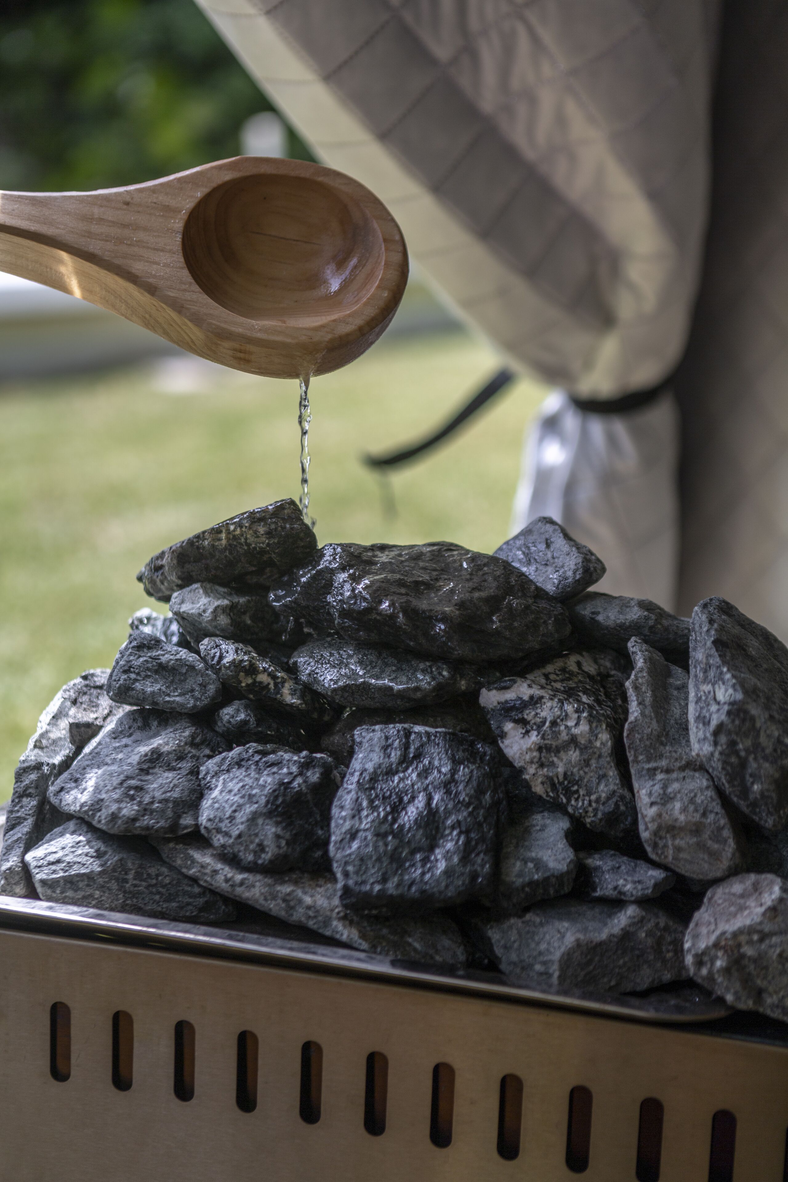 A wooden spoon pouring water onto a pile of rocks.