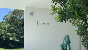 A building with a sign reading "JUSANDI" and a bronze statue of a lion on a pedestal. - Jusandi (Ishigaki)