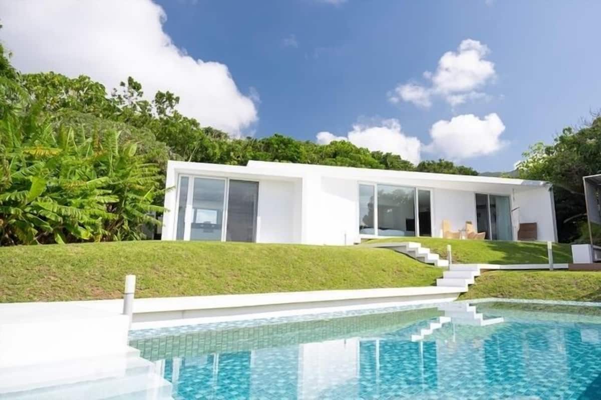 A modern house with a swimming pool, large glass doors, and a well-maintained lawn.