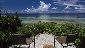 A view of the ocean from a patio with two wicker chairs and a wooden table. - Jusandi (Ishigaki)