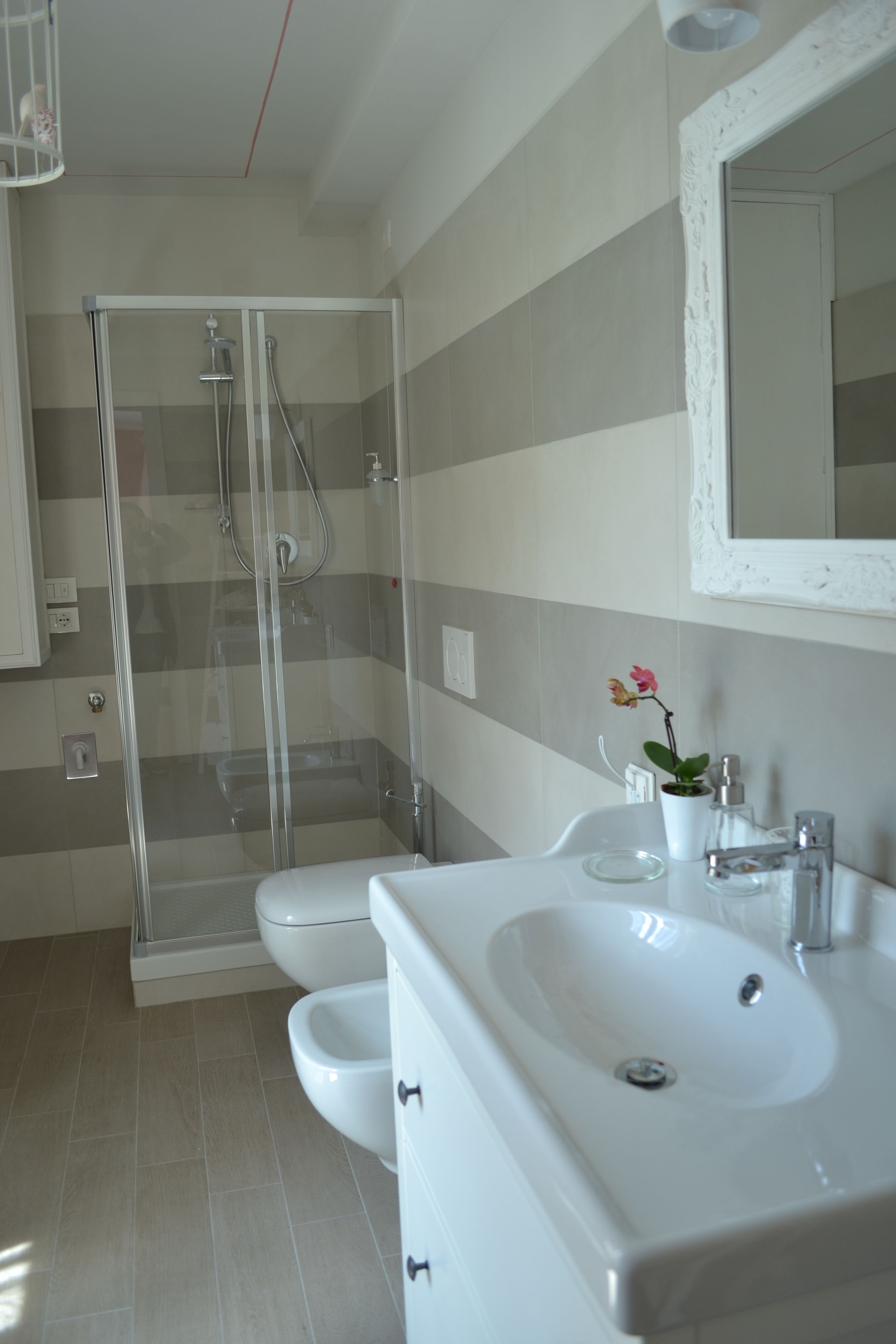 A modern bathroom with a glass-enclosed shower, a white sink, and a mirror above the sink.