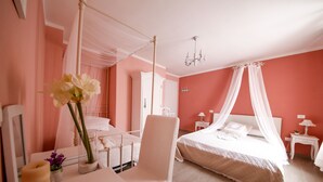 A bedroom with a canopy bed, a bedside table with a lamp, and a chair.