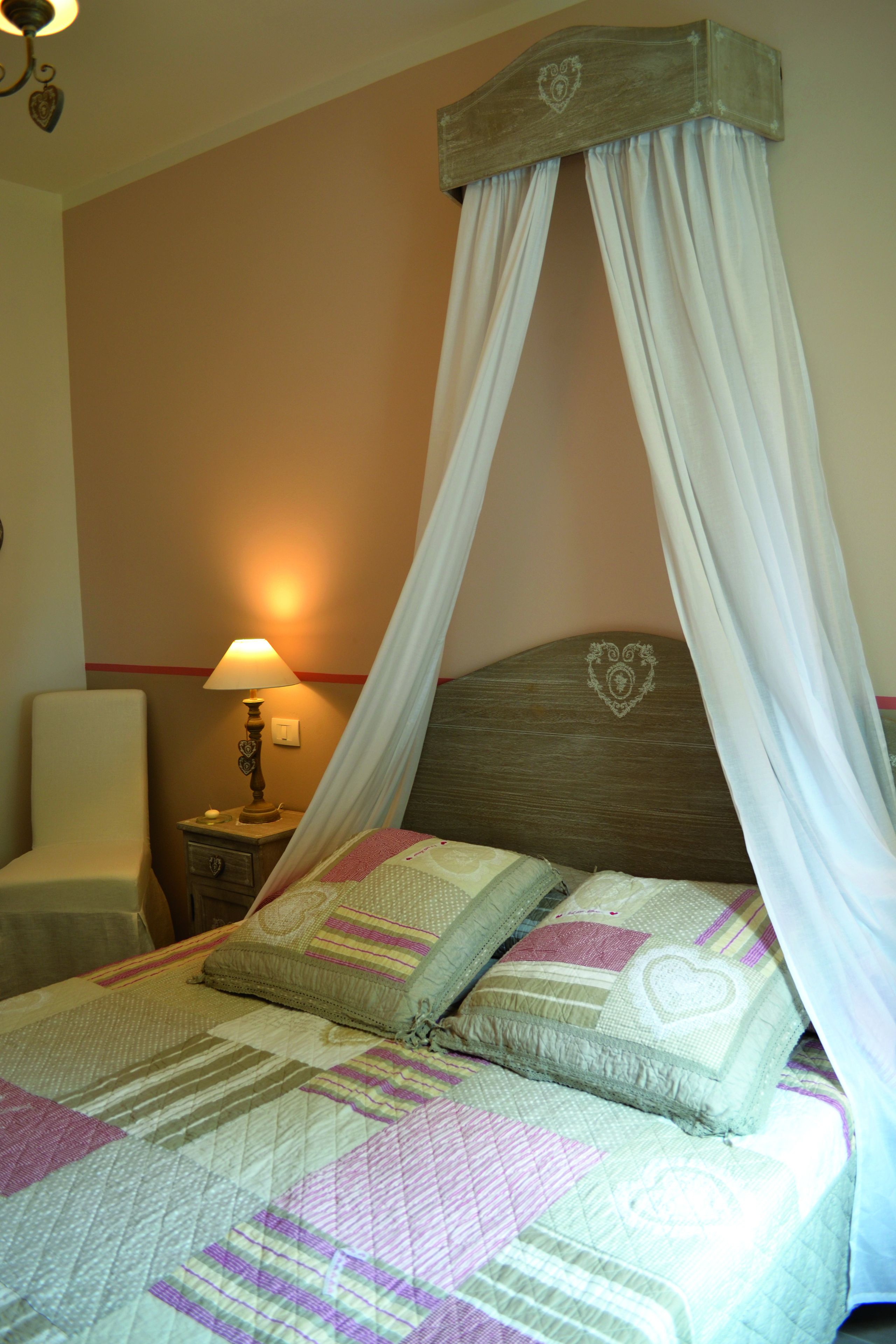 Un dormitorio con cama, mesita de noche, lámpara y una silla.