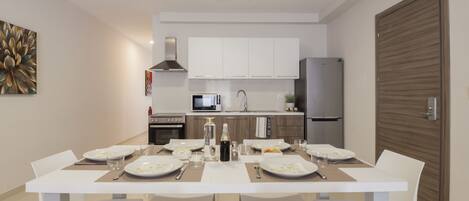 A modern kitchen with white cabinets, a stainless steel range hood, and a built-in microwave.